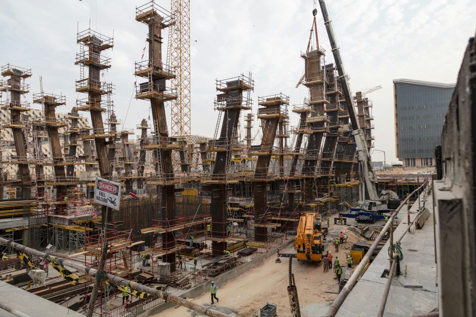 A bustling construction site with towering steel frameworks and cranes under a cloudy sky